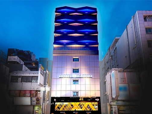 夜の街並みに建つ和風モダンな建物の外観で、看板「MINATO」が温かくライトアップされている。